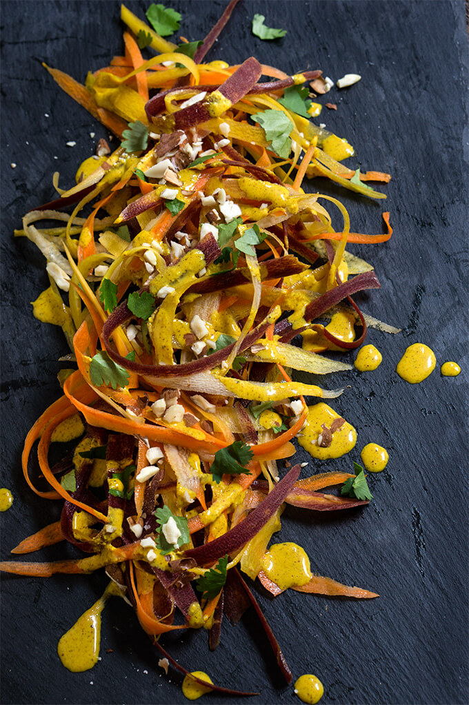 Carrot almond salad - ribbons of rainbow carrots, doused in creamy, turmeric coconut dressing, topped with toasted almonds and fresh cilantro - an explosion of exotic flavors that will surely tantalize your taste buds! | www.viktoriastable.com