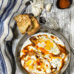 Eggs in garlicky yogurt {butter paprika sauce + feta cheese} Eggs in garlicky yogurt - crispy fried egg whites and soft yolks, drizzled with butter paprika sauce, and served over a bed of cold, creamy garlicky yogurt - this is the ultimate egg dish to dig in with a piece of toasted bread! | www.viktoriastable.com