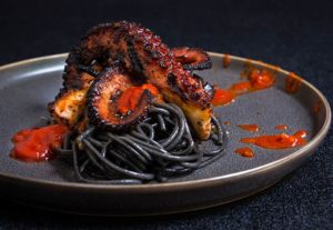 Grilled octopus over squid ink pasta and tomato garlic sauce | www.viktoriastable.com